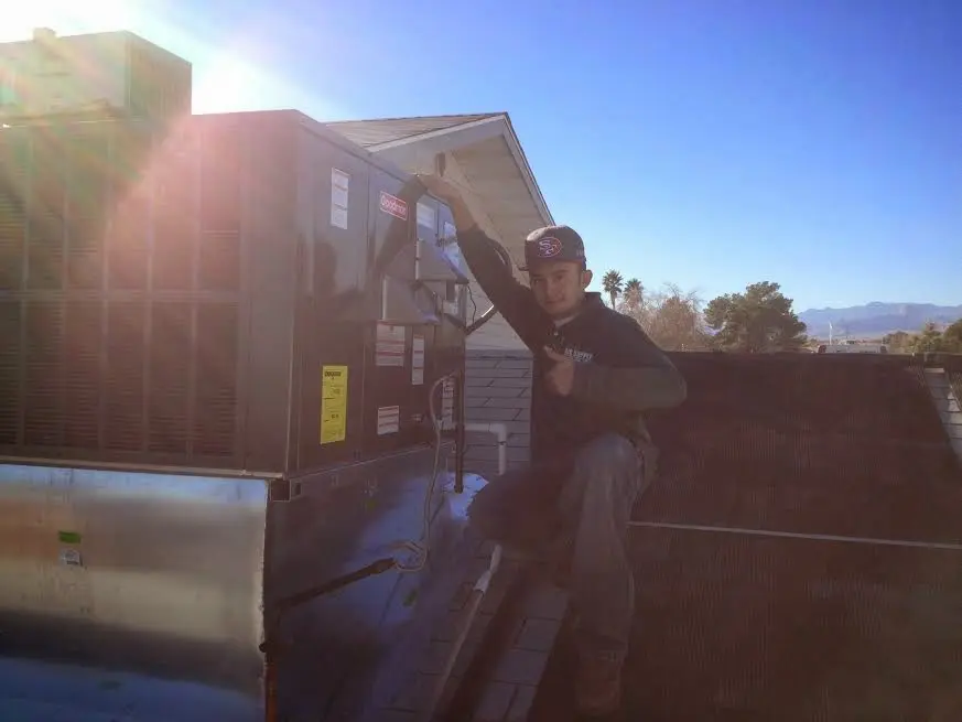 HVAC technician performing AC Tune-Up on a rooftop unit in East Riverdale